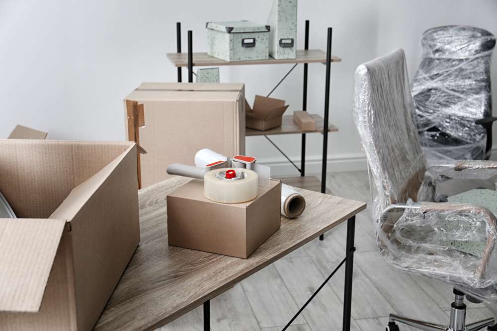 moving supplies across the living room to move into new home using professional moving company with boxes and tape using a company found through seo and social media marketing