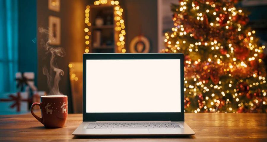 business owner using laptop computer in front of winter holiday decorations while strategizing winter marketing strategies for seasonal seo for summer services peak seasonal work