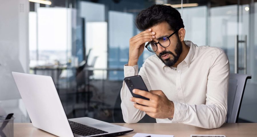 man stressed on his phone with laptop