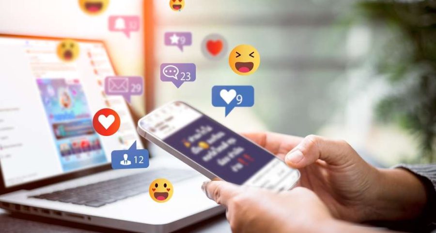 Iphone receiving likes and comments with a laptop behind it